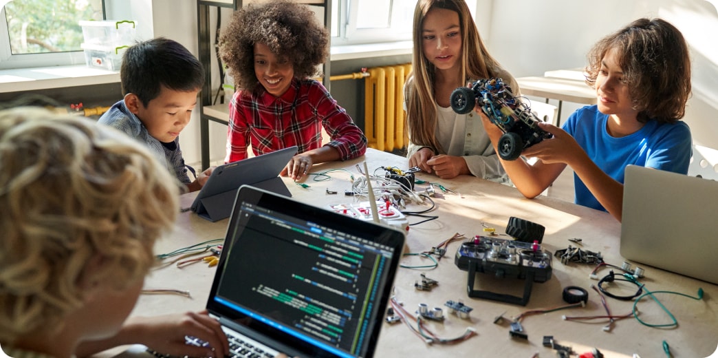 group of kids learning how to fix a remote control car