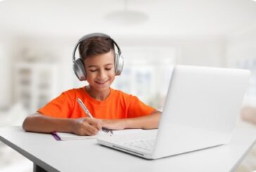 kid writing in notebook and wearing headphones
