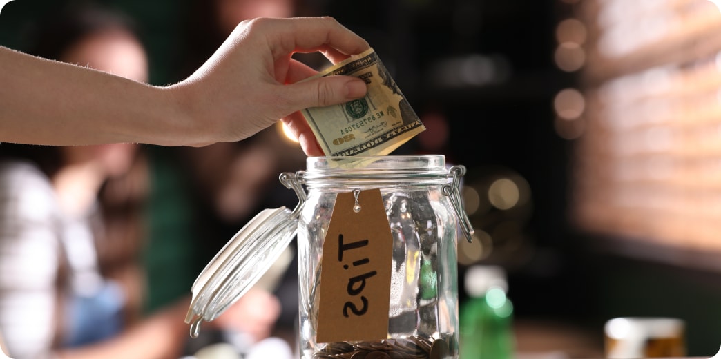 woman putting cash into tip jar
