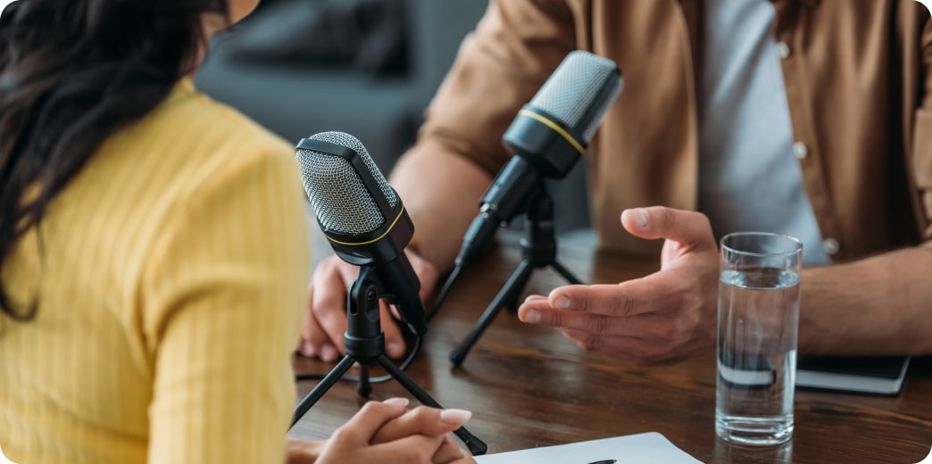 woman and gentleman speaking into microphones for podcast