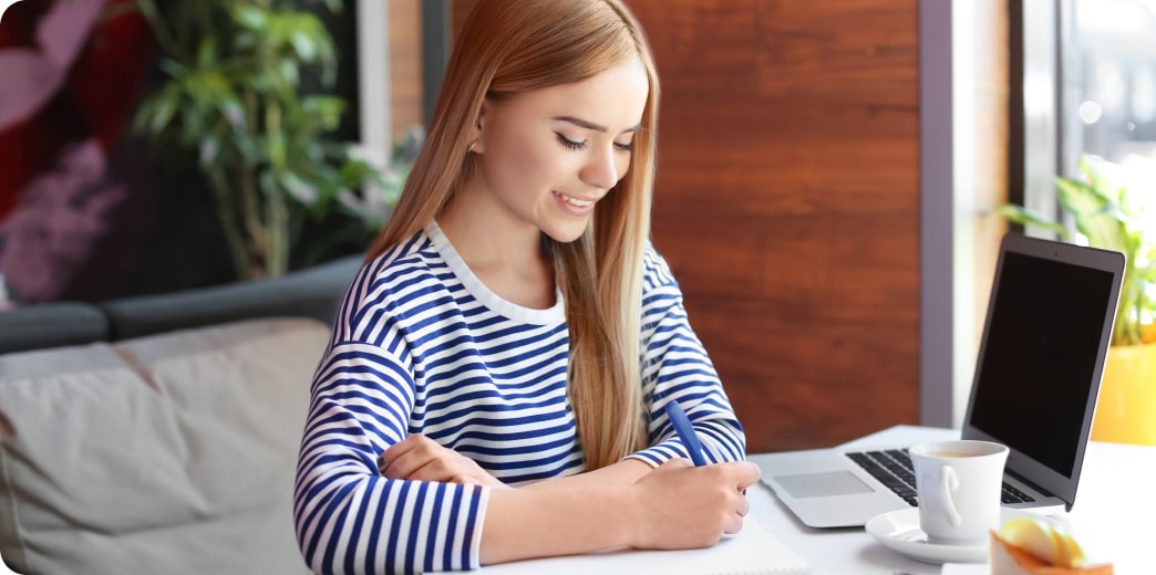 student smiling and reading notes in notebook