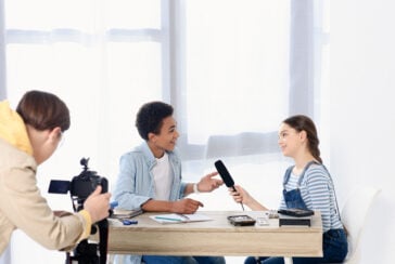 Picture of a caucasian teen kid conducting interview with african american friend for video blog