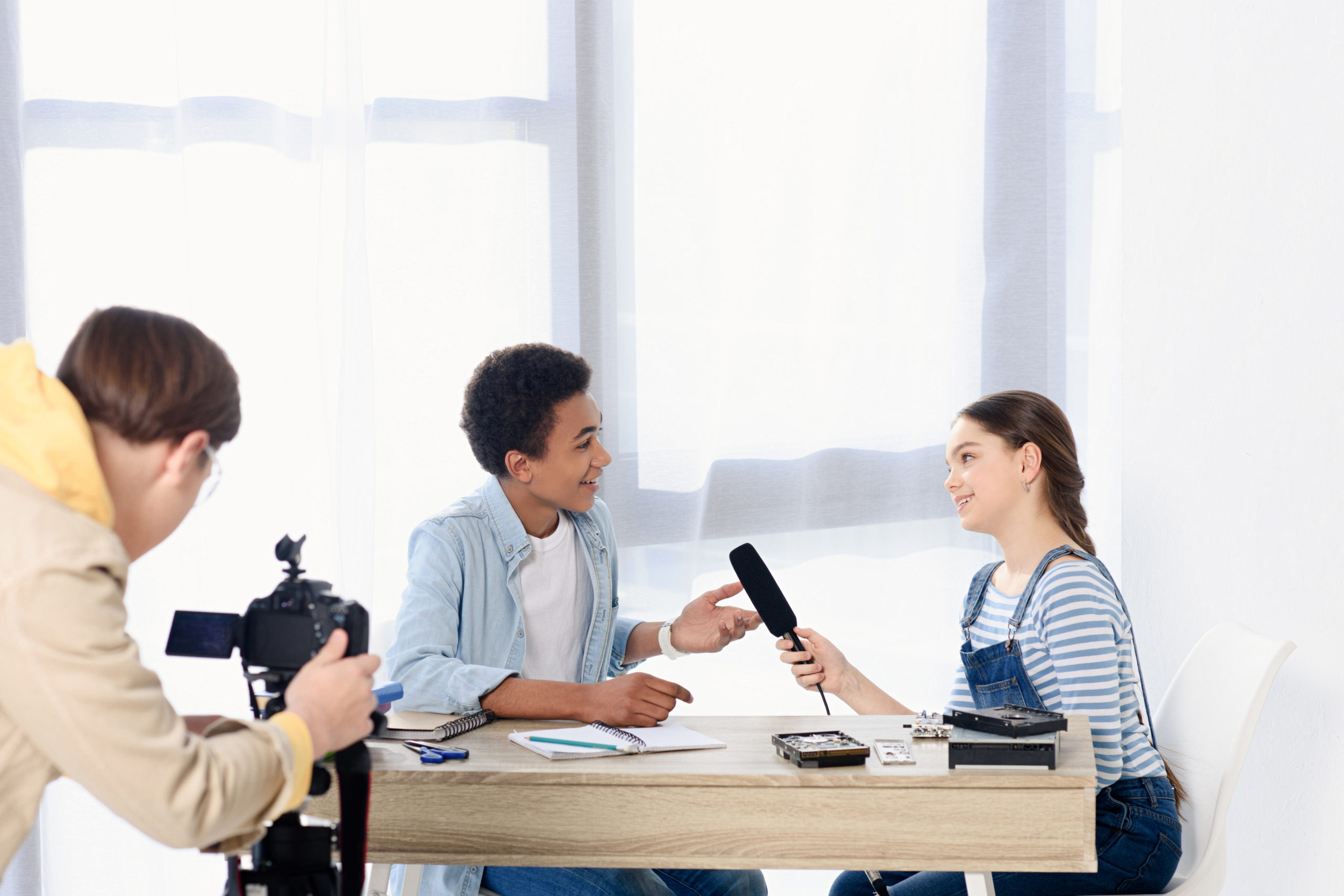 Picture of a caucasian teen kid conducting interview with african american friend for video blog