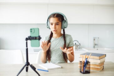 Fille enregistrant une vidéo en utilisant son téléphone sur un trépied.