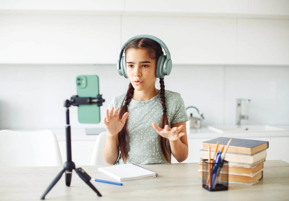 Girl recoding a video using her phone on a tripod.