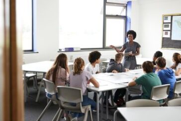 Photo d'une tutrice de lycée debout à table avec des élèves donnant des cours